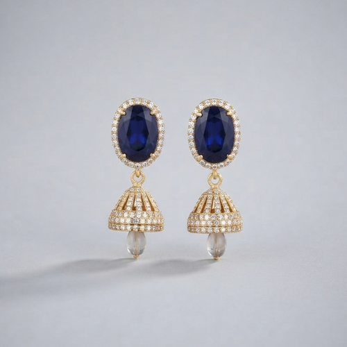 A pair of gold drop earrings featuring oval deep blue gemstones surrounded by small clear stones, with dangling bell-shaped gold sections set with clear stones and small pearl-like drops at the bottom, shown on a light gray background.
