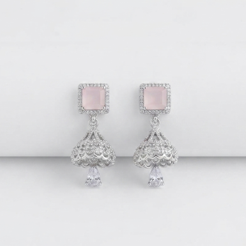 A pair of silver-toned dangle earrings featuring square pale pink stones surrounded by small clear stones, with ornate filigree drops and teardrop-shaped clear stones below, shown on a clean light gray background.