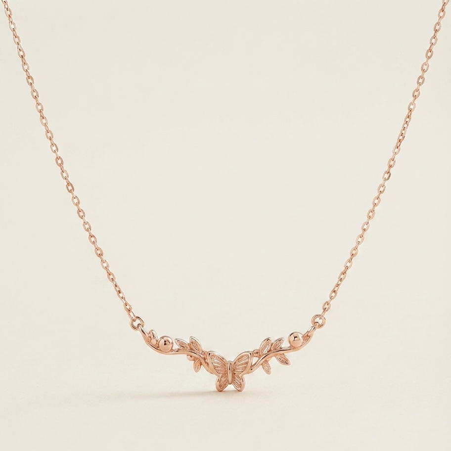 A delicate rose gold chain necklace featuring a small central pendant with a stylized leaf or vine motif, displayed against a clean, solid off-white background.