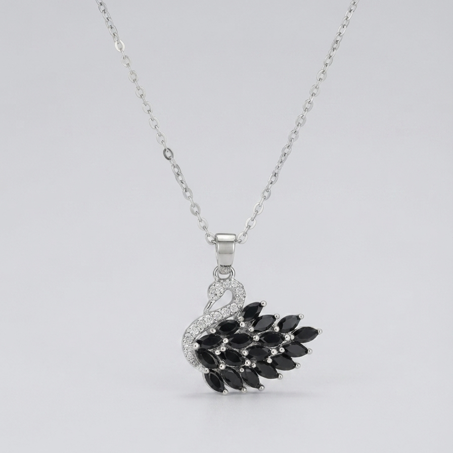 A silver-toned necklace featuring a pendant shaped like a swan with a black leafy branch for its body, set against a plain light gray background.